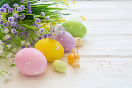 Easter eggs and flowers decoration on rustic wooden background. Vintage style toned picture. Rabbits toys.の写真素材