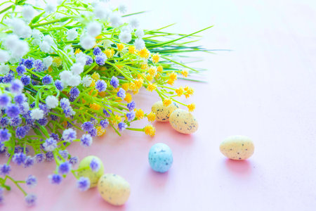 Spring flowers with easter eggs on a pink wooden background.