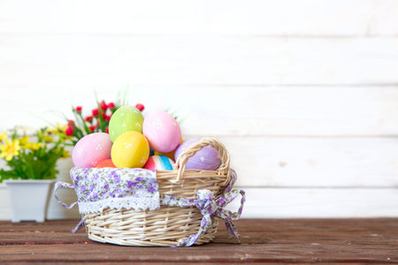 Colored easter eggs in the basket and spring flowers on wooden background. Greeting card.の写真素材