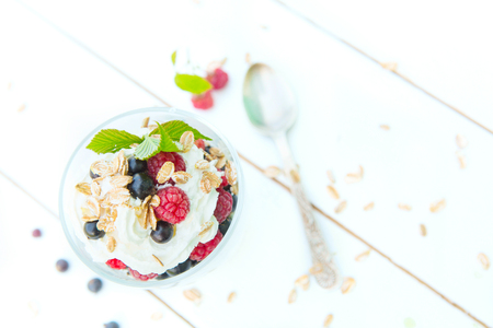 Healthy breakfast: layered dessrt yogurt parfait with fresh raspberries and black currant on wooden table over garden.の写真素材