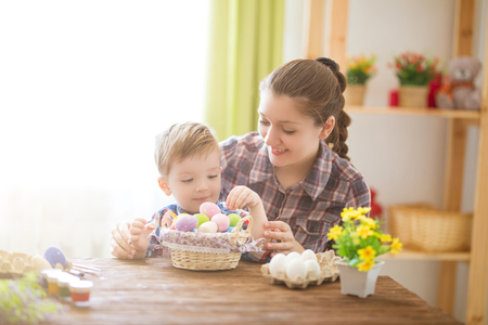 Easter concept. Happy mother and her cute child getting ready for Easter by painting the eggs.の写真素材