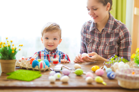 Easter concept. Happy mother and her cute child getting ready for Easter by painting the eggs.の写真素材