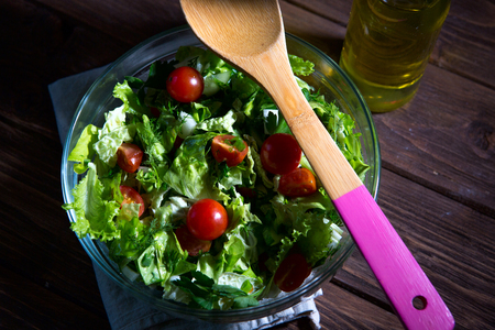 Fresh mixed green salad in bowl on wooden table close up. Concept healthy lifestyle and simple food.の写真素材