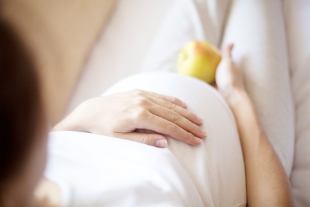 Pregnancy. Healthy food - pregnant woman with green apple at home.の写真素材