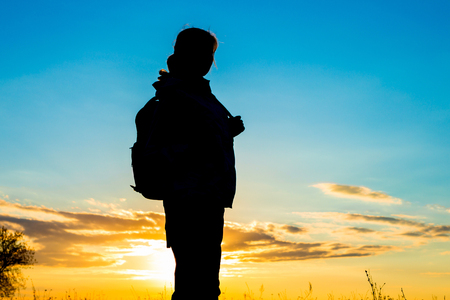 Silhouette of woman tourist over sunset sky.の写真素材