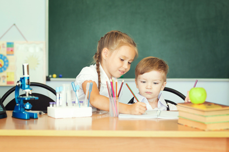 Cute girl and her little brother learning together.の写真素材
