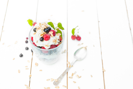 Healthy breakfast: layered dessrt yogurt parfait with fresh raspberries and black currant on wooden table over garden.の写真素材