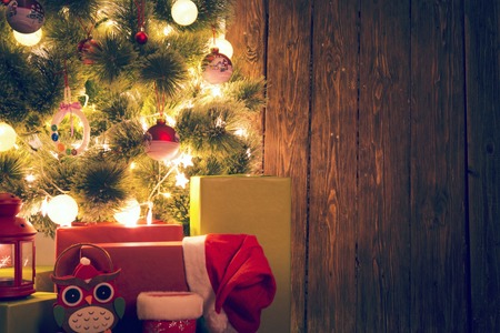 Decorated Christmas tree near wooden wall background for text.の写真素材