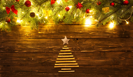 Christmas fir tree branches with toys on wooden table. Christmas background with fir tree and decoration with Christmas tree for dry sticks on dark wooden board.の写真素材