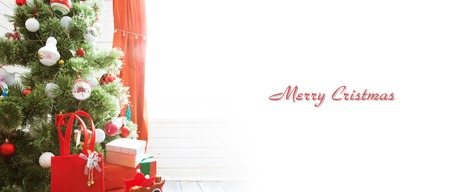 Elegant christmas tree with decorations and gifts on elegant hardwood floor over window.の写真素材