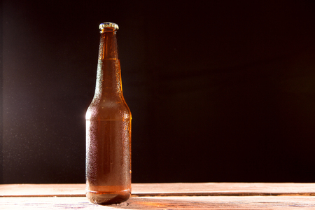 Bottle of beer on wooden table on a black backgroundの写真素材