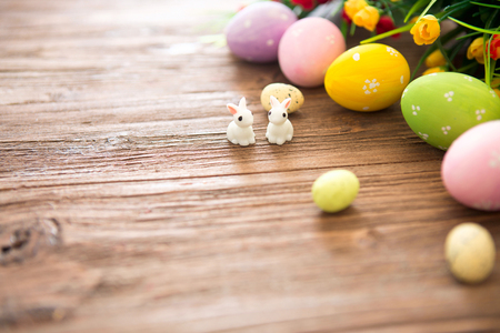 Easter eggs and Easter rabbits toys with flower on a wooden table.の写真素材
