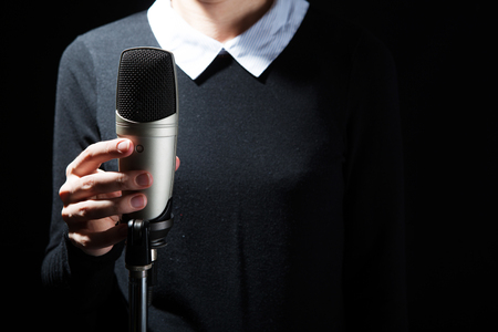 Female singer on the stage holding a microphone on a dark backgroundの写真素材