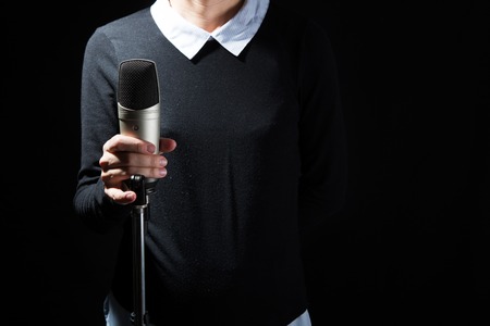 Female singer on the stage holding a microphone on a dark backgroundの写真素材