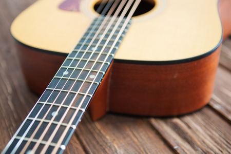 Close up of acoustic guitar with metal strings on a wooden table. Music concept.の写真素材