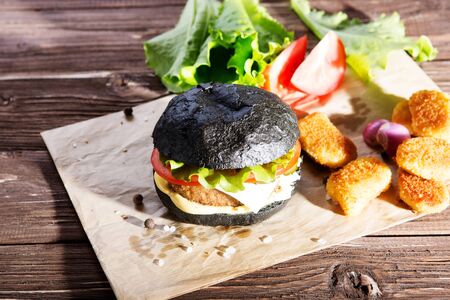 Delicious fast food. Tasty burger with bacon on table against black background. Space for textの写真素材