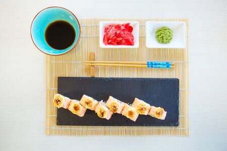 Sushi rolls with salmon and hot tea ceremony on a black wooden table. Fried hot Roll with salmon, avocado, cucumber. Healthy and tasty food.の写真素材