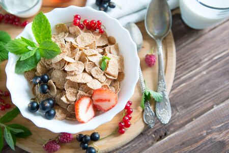 Healthy breakfast with cornflakes and fresh berries on white wooden Healthy tasty breakfast multigrain wholewheat healthy cereals with strawberries, raspberries, black currants and red currants.の写真素材