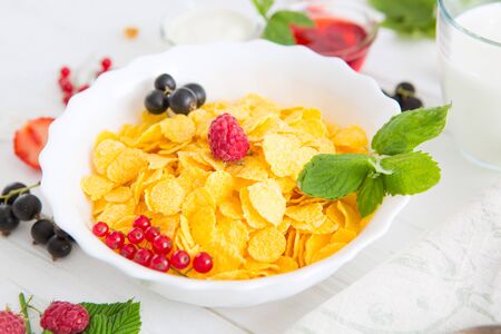 Fresh corn flakes with strawberries and milk close up Healthy tasty breakfast cornflakes with strawberries, raspberries, black currants and red currants.の写真素材