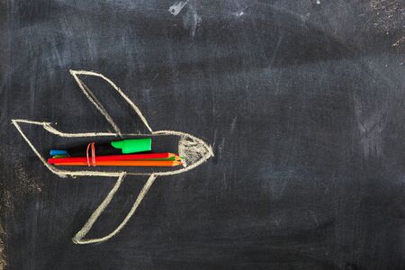 Back to school. Chalked drawing of an airplane on a school blackboard with school supplies and an empty place for your text or design.の写真素材