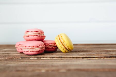Sweet colorful French macaroon cookies dessert on brown wooden table over white wooden backgroundの写真素材