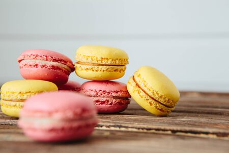 Sweet colorful French macaroon cookies dessert on brown wooden table over white wooden backgroundの写真素材