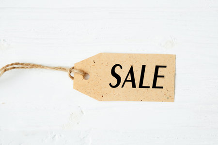 price tag label with word SALE on wooden background One paper blank tags with word SALE with rope on...