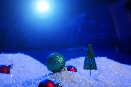 Christmas background with Christmas balls on snow over fir-tree, night sky and moon. Shallow depth...