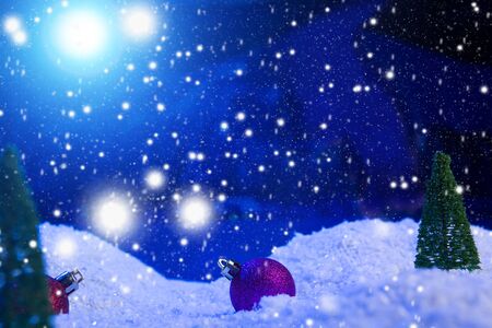 Christmas background with Christmas balls on snow over fir-tree, night sky and moon. Shallow depth of field. Christmas background. Fairy tale. Macro. Artificial magic dreamy world.の写真素材