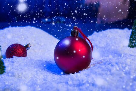 Christmas background with Christmas balls on snow over fir-tree, night sky and moon. Shallow depth of field. Christmas background. Fairy tale. Macro. Artificial magic dreamy world.の写真素材