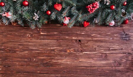 Christmas fir tree with decoration on a wooden board Blurred Christmas background, with fir branches, fairy lights and christmas decorations on brown wooden plankの写真素材