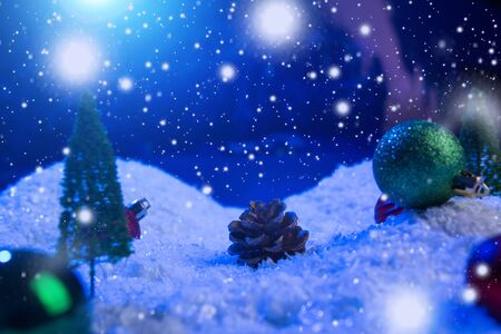 Christmas background with Christmas balls on snow over fir-tree, night sky and moon. Shallow depth of field. Christmas background. Fairy tale. Macro. Artificial magic dreamy world.の写真素材