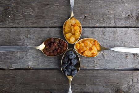 raisins in metal spoons on wooden table. Rustic style.の写真素材