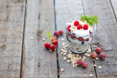 Healthy layered dessert with yogurt, black currant and raspberries on wooden backgroundの写真素材