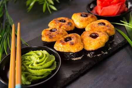Set of baked sushi rolls with wasabi and ginger on a black background. Japanese oriental cuisineの写真素材