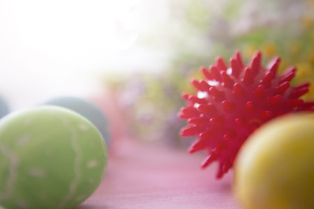 Virus model of Coronavirus disease COVID-19 with colorful easter eggs with flowers on a pink wooden...