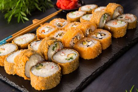Set of fried sushi rolls with wasabi and ginger on a black background. Japanese oriental cuisineの写真素材