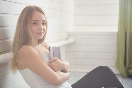 Student and education concept. Woman with book on the wooden white floor over window at home
