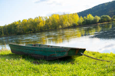 River and old boat on shore in the mountains in autumn on a sunny warm day.の写真素材