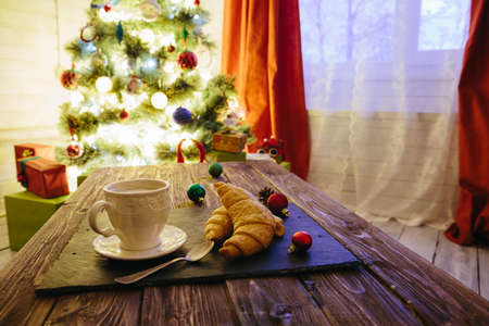 Mug with hot chocolate on a wooden table with Christmas decorations on a background of the Christmas treeの写真素材