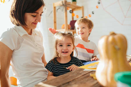 Happy Halloween. Attractive young woman with her little cute kids are preparing to Halloween on kitchen having fun with pumpkins. Happy Halloween conceptの写真素材