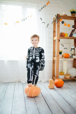 The little boy in a skeleton costume is ready to celebrate Halloween. Boy in a halloween dress-up room.の写真素材
