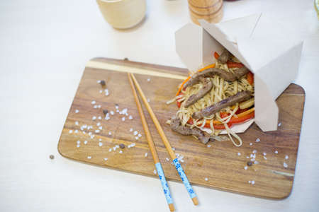 Noodles with vegetables in take-out box on wooden table Healthy and tasty food.の写真素材