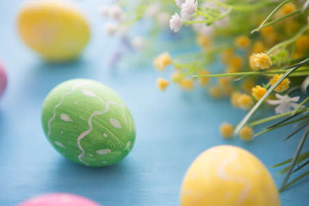 Easter eggs decoration with flowers on blue wooden tableの写真素材