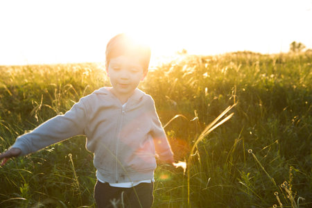 A boy runs across the field on a hot summer day against the sunsetの写真素材