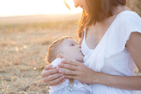 Beautiful happy mother breastfeeding her baby boy outdoor.の写真素材