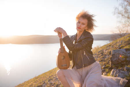 Woman with guitar ukulele in the mountains, amazing landscape, stunningly beautiful nature, mountains, sunset Hiking in the mountainsの写真素材