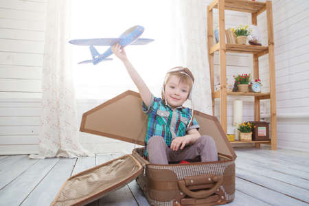 Children boy wearing pilot costume making ready to fly gesture standing on living room wooden floor at homeの写真素材