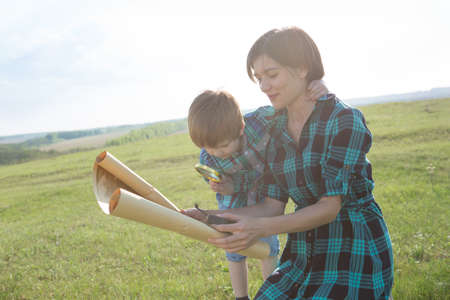 This world without borders. Go to new adventures and discoveries. A beautiful young mother with her son looks at a map of the world and decide where to go on a tripの写真素材