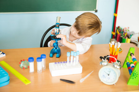 Child with curiosity during a medicine fair looking at bacteria through a microscope and learning...
